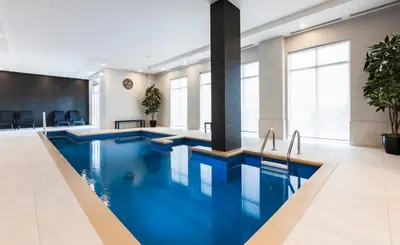 a large pool with blue water in a building at Imperia Hôtel et Suites Boucherville in Boucherville