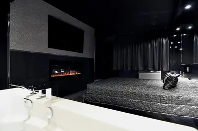 a black bedroom with a bed and a fireplace at Complexe Hotelier Le 55 in Bécancour