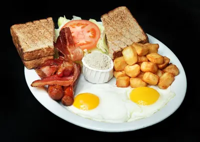 a plate of breakfast food with eggs bacon and toast at Complexe Hotelier Le 55 in Bécancour