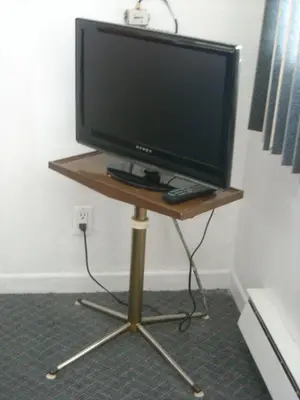 a television on a stand with a remote control at Motel le Verseau in Sorel