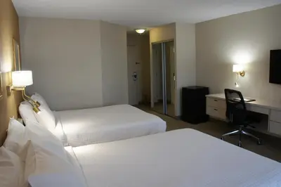 a hotel room with two beds and a desk at Hôtel Castel in Granby