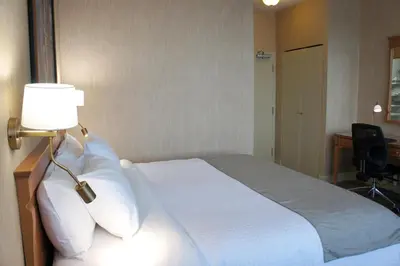 a bedroom with a bed with a lamp and a desk at Hôtel Castel in Granby