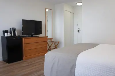 a bedroom with a bed and a tv on a dresser at Hôtel Castel in Granby