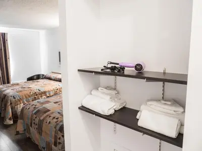 a room with a bed and towels on shelves at Motel Classique in Joliette