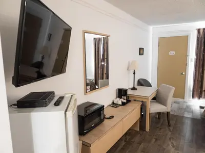 a living room with a television and a desk with a computer at Motel Classique in Joliette