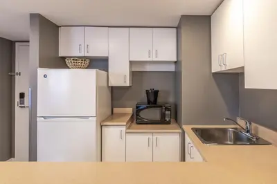 a kitchen with white cabinets and a white refrigerator at Hotel Faubourg Montreal Centre-Ville Downtown in Montréal