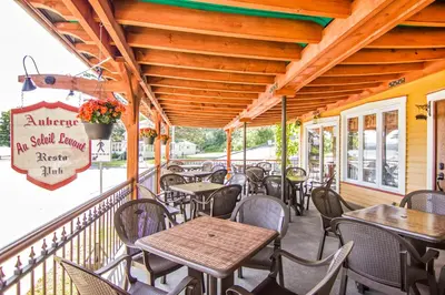 an outdoor patio with tables and chairs on a building at Auberge Au Soleil Levant in Piopolis