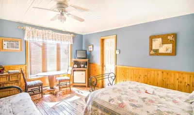 a bedroom with a bed and a desk and a window at Auberge Au Soleil Levant in Piopolis