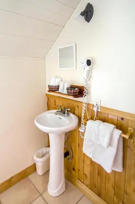 a bathroom with a sink and towels on a wall at Auberge Au Soleil Levant in Piopolis