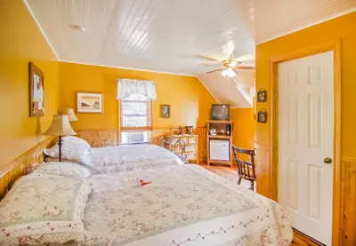 a bedroom with a large bed and yellow walls at Auberge Au Soleil Levant in Piopolis