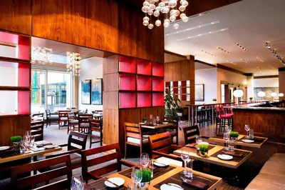 a restaurant with wooden tables and chairs and a bar at Le Westin Montreal in Montréal