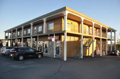 a building with a car parked in a parking lot at Hotel Motel Le Château in Lac-Mégantic