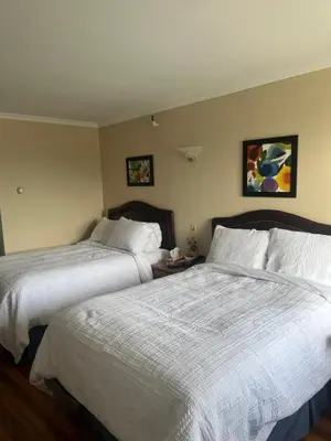 two beds in a hotel room with two beds at Hotel Motel Le Château in Lac-Mégantic