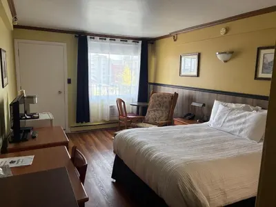 a hotel room with a bed and a desk and a chair at Hotel Motel Le Château in Lac-Mégantic