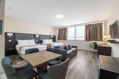 a hotel room with two beds and a table and chairs at Hotel Montreal Metropolitan, BW Signature Collection in Montréal