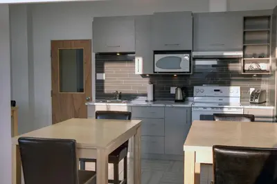 a kitchen with gray cabinets and a table with chairs at Suite Marie-Thérèse in Vallée-Jonction