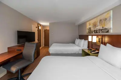 a hotel room with two beds and a television at Comfort Inn South in Brossard