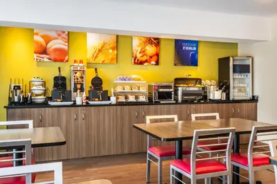 a restaurant with yellow walls and tables and chairs at Comfort Inn South in Brossard
