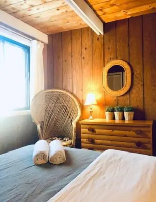 a bedroom with a bed with a chair and a mirror at Le Rustique Orford Domaine Cheribourg in Magog-Orford
