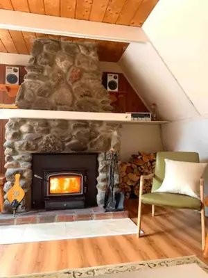 a living room with a stone fireplace and a green chair at Le Rustique Orford Domaine Cheribourg in Magog-Orford
