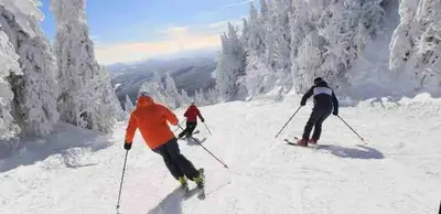 three people are skiing down a snow covered slope at Le Cocon Orford Domaine Cheribourg in Magog-Orford
