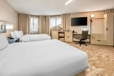 a hotel room with two beds and a desk at Comfort Inn in Laval