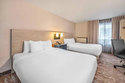 a hotel room with two beds and a chair at Comfort Inn in Laval
