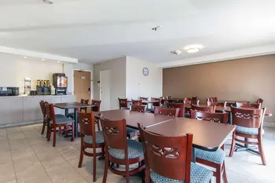 a dining room with tables and chairs and a kitchen at Comfort Inn in Trois-Rivières