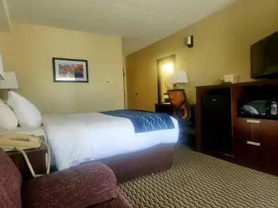 a hotel room with a bed and a couch and a television at Comfort Inn in Trois-Rivières