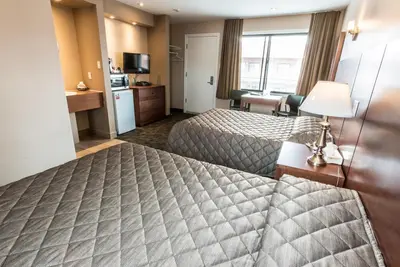 a hotel room with two beds and a television at Motel Falcon in Brossard