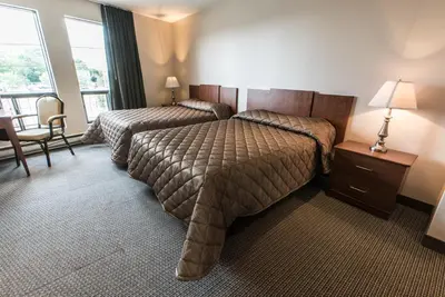 a hotel room with two beds and a desk and window at Motel Falcon in Brossard