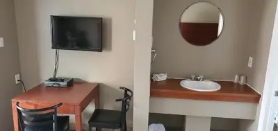 a bathroom with a sink and a mirror and a tv at Motel Falcon in Brossard