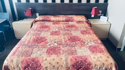 a bedroom with a bed with a quilt on it at Motel Falcon in Brossard