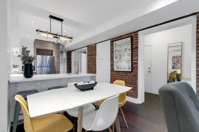 a kitchen and dining room with a white table and chairs at LiV MTL Soho in Montréal
