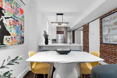 a dining room with a white table and yellow chairs at LiV MTL Soho in Montréal