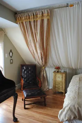 a bedroom with a chair and a bed and a window at Auberge Marquis de Montcalm in Sherbrooke