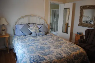 a bedroom with a bed with a blue and white comforter at Auberge Marquis de Montcalm in Sherbrooke