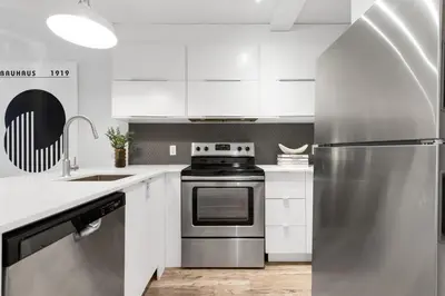 a kitchen with white cabinets and a stainless steel refrigerator at LiV MTL Urban in Montréal