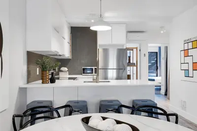 a kitchen with white cabinets and a table and chairs at LiV MTL Urban in Montréal