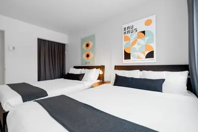 two beds in a hotel room with white walls at LiV MTL Urban in Montréal