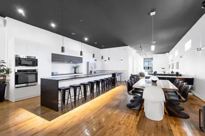 a kitchen with white walls and black and white tables and chairs at LiV MTL Plaza in Montréal