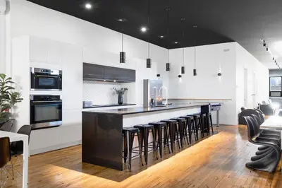 a kitchen with white cabinets and a black island with bar stools at LiV MTL Plaza in Montréal