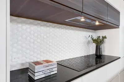 a kitchen with a black counter top and white tiles at LiV MTL Plaza in Montréal