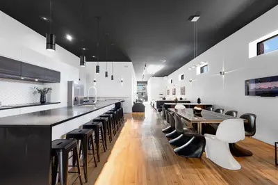 a kitchen with a long bar with black and white chairs at LiV MTL Plaza in Montréal