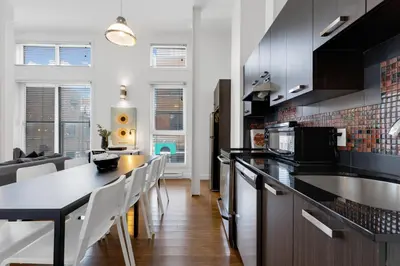 a kitchen with black countertops and white cabinets at LiV MTL Main in Montréal