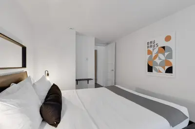 a white bedroom with a large bed with white sheets at LiV MTL Main in Montréal