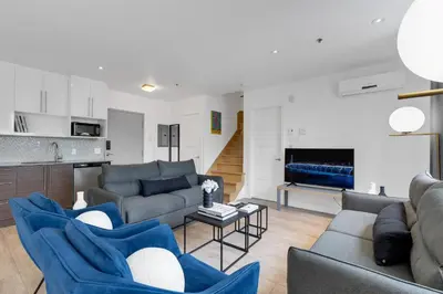 a living room with blue couches and a kitchen at LiV MTL Downtown in Montréal