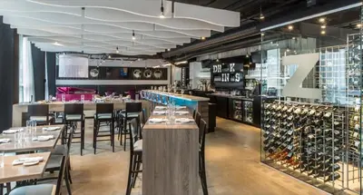 a restaurant with tables and chairs and wine racks at Hotel Zero 1 Montreal in Montréal