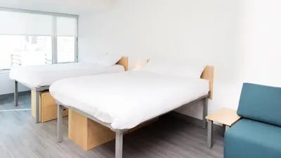 two beds in a hospital room with a couch at Campus1 MTL Student Residence Downtown Montreal in Montréal