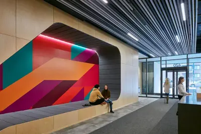 two people sitting on a bench in a building with a colorful wall at Campus1 MTL Student Residence Downtown Montreal in Montréal